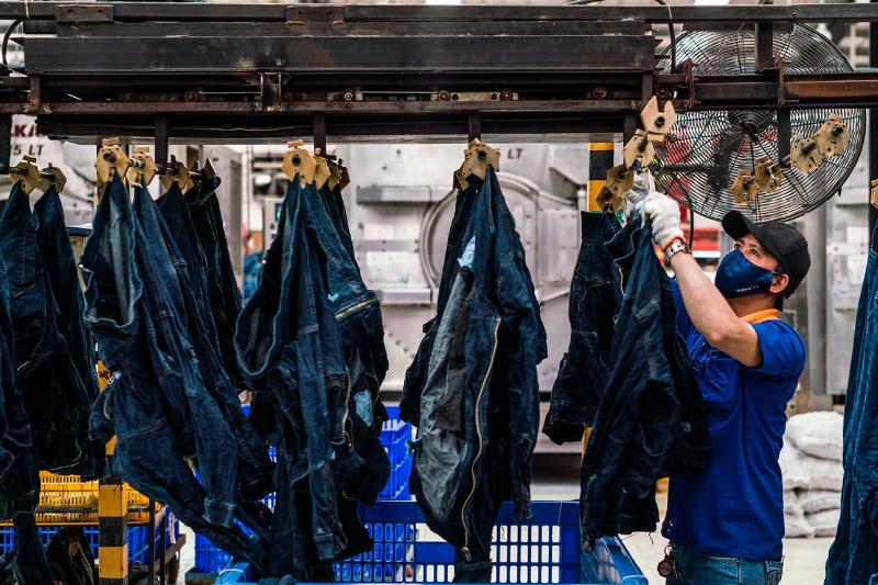 Một công nhân đang mặc bộ yếm (overalls) màu xanh dương khi làm việc trong nhà máy